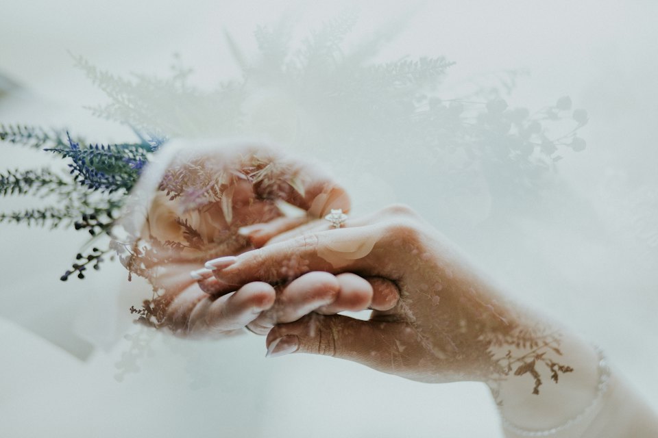 In-camera double exposure of two hands and a ring layered with lavender and fern.